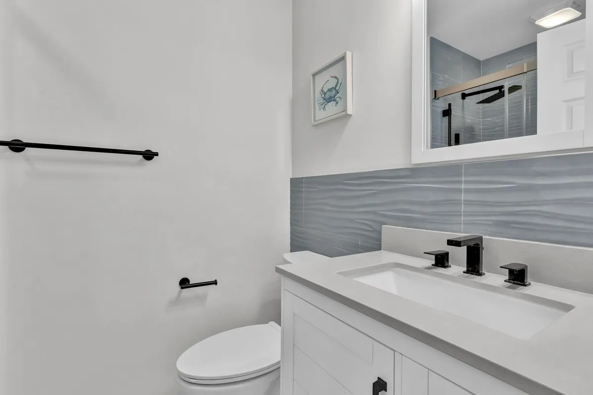 A serene, modern bathroom with a stylish sink, large mirror, and a spacious shower enclosed in glass. The ambiance is quiet and calming, perfect for personal grooming and relaxation after a day of adventure.