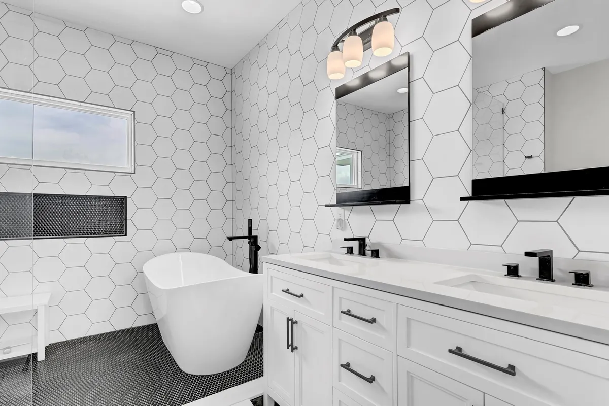 A luxurious spa-inspired bathroom equipped with a freestanding bathtub, dual sink vanity, and a sophisticated hexagonal tile pattern. The clean lines and elegant fixtures offer a sense of indulgence and tranquility.