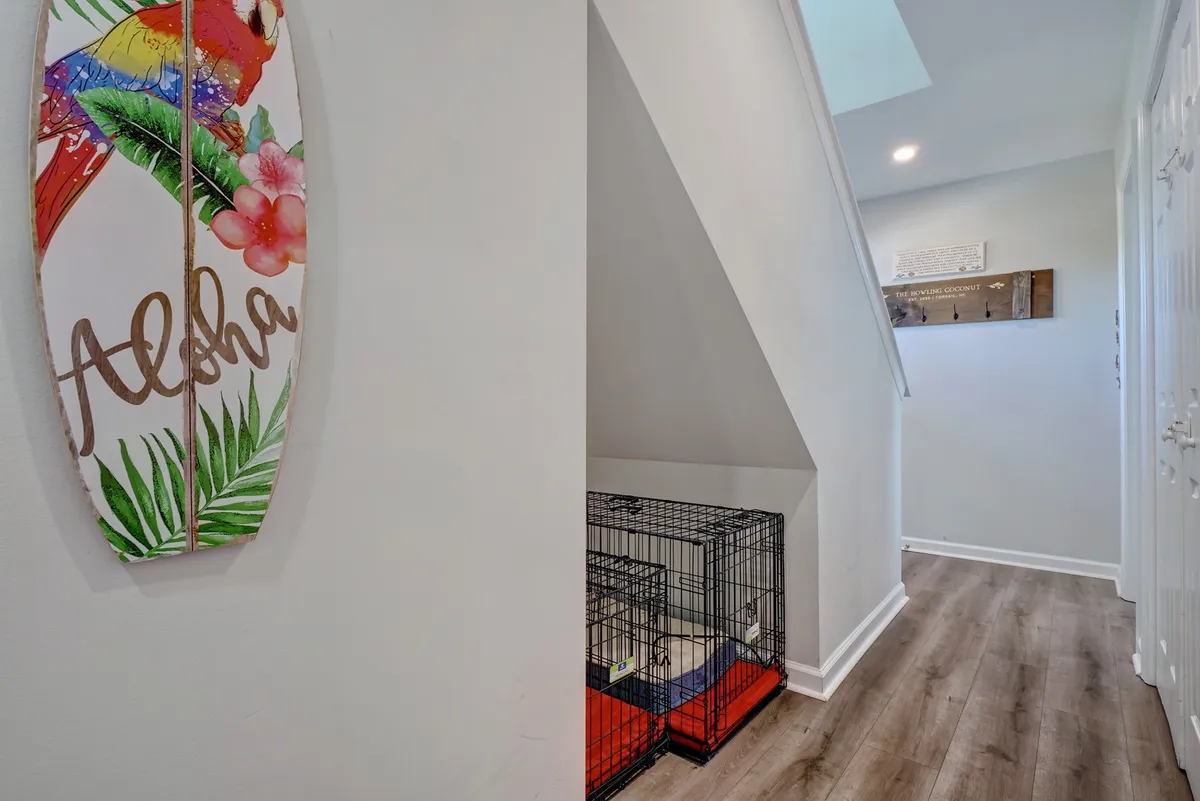 Inside the home’s entrance, a surfboard with an 'Aloha' inscription adds charm while a pet crate sits ready for use. The scene feels welcoming to both human and canine guests, suggesting comfort and convenience right from the first step inside.